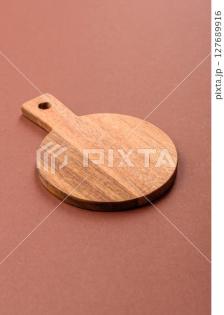 Empty wooden cutting board on a monochrome brown background 127689916