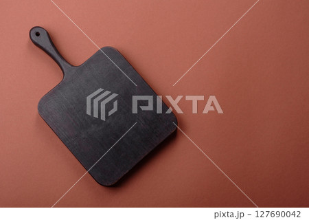 Empty wooden cutting board on a monochrome brown background 127690042