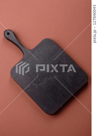 Empty wooden cutting board on a monochrome brown background Empty wooden cutting board on a monochrome brown background 127690043