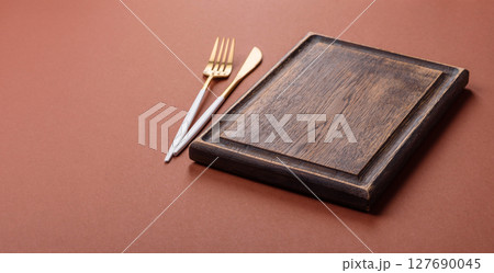 Empty wooden cutting board on a monochrome brown background 127690045
