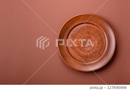 Empty ceramic plate on a monochrome brown background Empty ceramic plate on a monochrome brown background 127690066