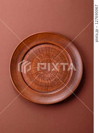 Empty ceramic plate on a monochrome brown background 127690067