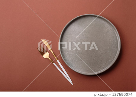 Empty ceramic plate on a monochrome brown background 127690074