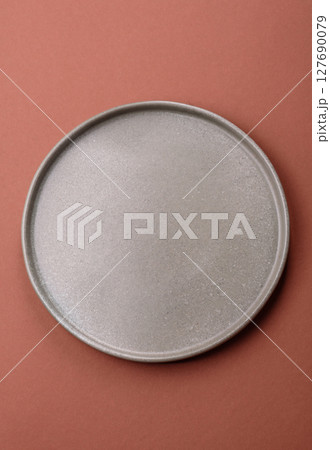 Empty ceramic plate on a monochrome brown background Empty ceramic plate on a monochrome brown background 127690079