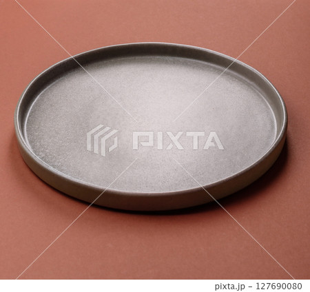 Empty ceramic plate on a monochrome brown background Empty ceramic plate on a monochrome brown background 127690080