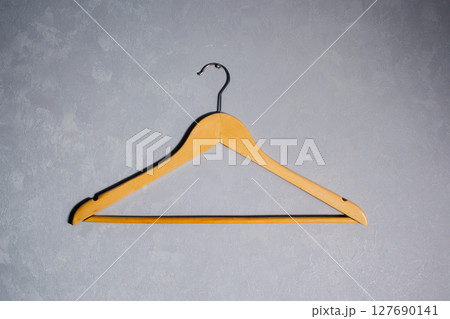 Wooden clothes hanger against grey wall. Minimalism concept. 127690141