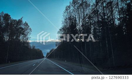 A Beautiful and Serene Highway at Dusk Surrounded by Lush Forests and Scenic Views Galore 127690333