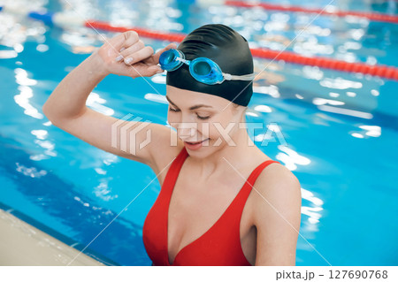Waist up of a cute young woman in red swimsuit in the pool 127690768