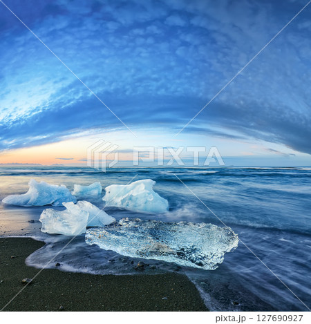 Impressive pieces of the iceberg sparkle on famous Diamond Beach at  Jokulsarlon lagoon during sunset. 127690927