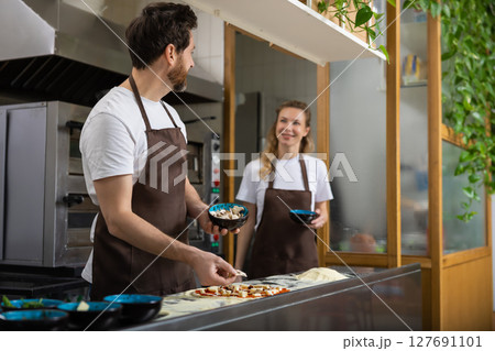 Man shaping dough with woman 127691101