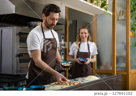 Man preparing pizza with woman Man preparing pizza with woman 127691102
