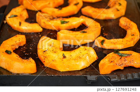 Bright orange butternut squash pieces with spices grilled on electric grill 127691248