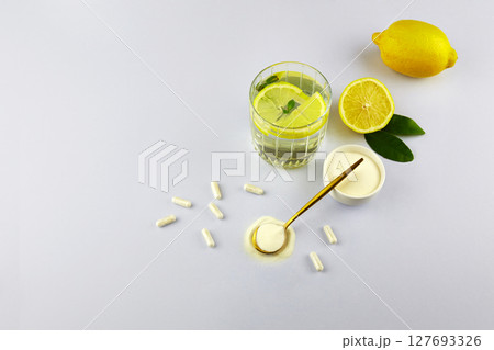 Collagen protein powder and pills, a glass of water with lemon. 127693326