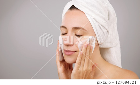 Adverstiring face cleansing foam. Woman using moisturizing foam for face washing and smiling, morning skincare routine. Studio isolated Grey Background. Beauty routine. Skincare treatment. Copy space Adverstiring face cleansing foam. Woman using moisturizing foam for face washing and smiling, morning skincare routine. Studio isolated Grey Background. Beauty routine. Skincare treatment. Copy space 127694521