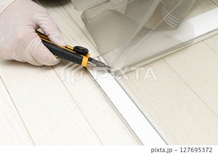 網戸の張り替え　防虫網を切って枠のコードをローラーで押し入れる 127695372