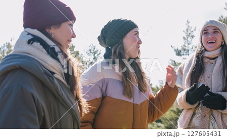 Three smiling women talking and enjoying winter day outdoors 127695431