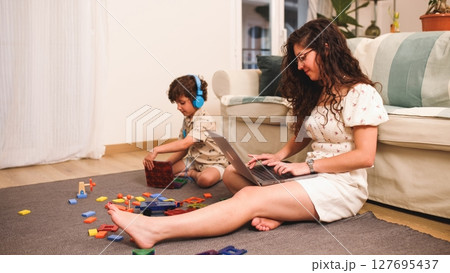 Mother working from home while child plays with toys 127695437