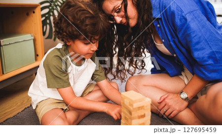 Mother and son playing wooden block game at home Mother and son playing wooden block game at home 127695459