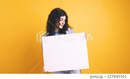 Young student woman showing blank whiteboard on yellow background 127695501