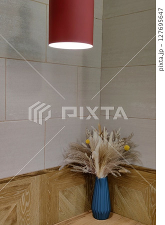 stylish corner featuring blue vase dried flowers illuminated by soft red light in interior. closeup. 127695647