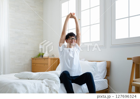 部屋で伸びをする男性 127696324