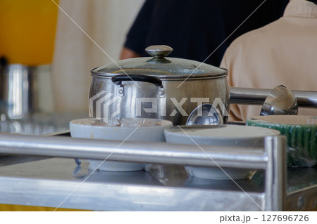 Close-up view of a large metal pot and serving bowls on a stainless steel buffet line 127696726