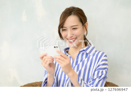 スマホで動画コンテンツを見る女性 スマホで動画コンテンツを見る女性 127696947