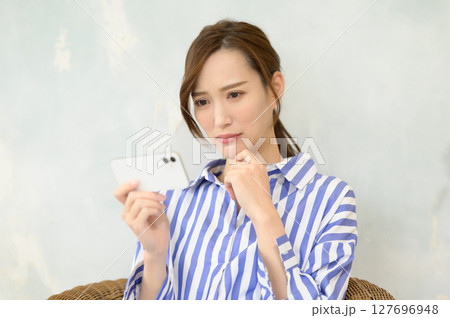 スマホで動画コンテンツを見る女性 スマホで動画コンテンツを見る女性 127696948