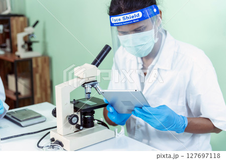Indian Scientist man look into Microscope research in science laboratory. Asian biochemistry scientist using microscope in laboratory chemistry labs. Covid-19 medical research scientific experiment Indian Scientist man look into Microscope research in science laboratory. Asian biochemistry scientist using microscope in laboratory chemistry labs. Covid-19 medical research scientific experiment 127697118