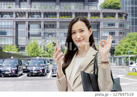 スマートフォンを持ちながらOKを出すビジネスウーマン 127697519