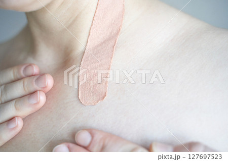 Caucasian adult female with skin tape on shoulder: close-up of healthcare 127697523