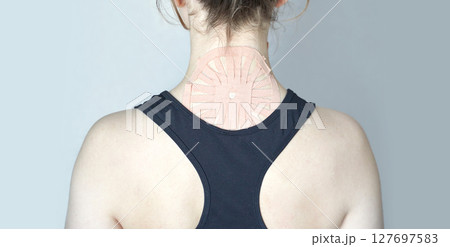 Caucasian female with therapeutic kinesiology tape on upper back for muscle 127697583