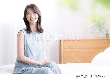 寝起きでベッドに座る女性の上半身 爽やかな朝のイメージ 振り返る 寝起きでベッドに座る女性の上半身 爽やかな朝のイメージ 振り返る 127697772