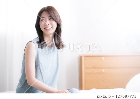 寝起きでベッドに座る女性の上半身 爽やかな朝のイメージ 振り返る 寝起きでベッドに座る女性の上半身 爽やかな朝のイメージ 振り返る 127697773