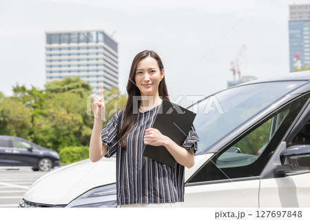 自動車の前で指差しをする女性 自動車の前で指差しをする女性 127697848