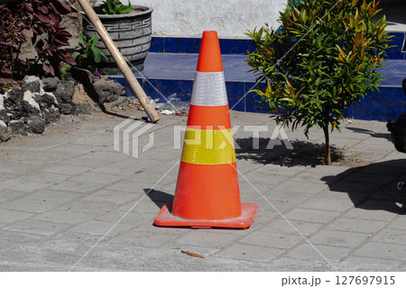 Safety First - Vibrant Orange Traffic Cone on Pavement 127697915