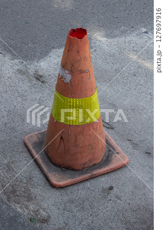 Weathered Road Marker - A Dilapidated Traffic Cone on Asphalt Weathered Road Marker - A Dilapidated Traffic Cone on Asphalt 127697916