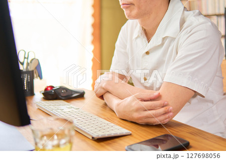 パソコンの画面を見つめて考えごとをする50代男性 パソコンの画面を見つめて考えごとをする50代男性 127698056