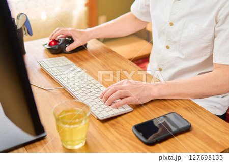 パソコン作業でマウスを操作しながらキーボード入力をする50代男性 パソコン作業でマウスを操作しながらキーボード入力をする50代男性 127698133