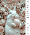 Easter Bunny with a pink egg on among flowers on pink background. 127698696