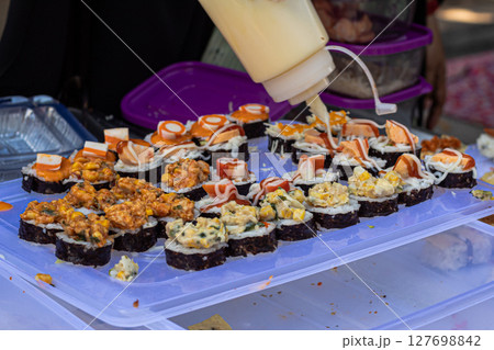 Assorted Sushi Rolls with Various Toppings at a Food Stall 127698842