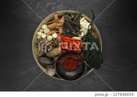 Mix composition of various exotic dried spices in natural bamboo bowl on black stone background Mix composition of various exotic dried spices in natural bamboo bowl on black stone background 127698859