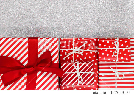 Various size wrapped in red paper with ornament Christmas gift boxes on shiny silver background 127699175