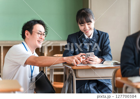スマホを使い授業をする教師と女子生徒（BYOD・ICT） 127700384