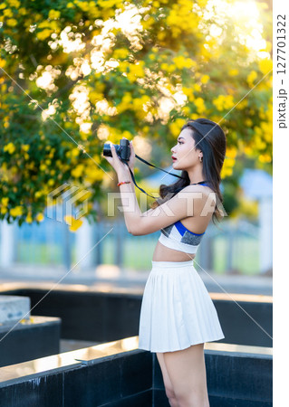 Portrait of beautiful athletic young asian woman in fashionable sportswear standing and with a holding the camera in garden the park,Outdoor travel sporty concept 127701322