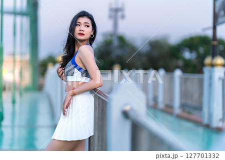 Portrait of beautiful athletic young asian woman in fashionable sportswear standing and having rest after exercise training on Route walking jogging or ride bicycle and exercise on the bridge. Portrait of beautiful athletic young asian woman in fashionable sportswear standing and having rest after exercise training on Route walking jogging or ride bicycle and exercise on the bridge. 127701332