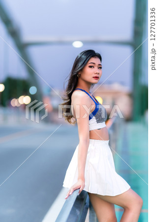 Portrait of beautiful athletic young asian woman in fashionable sportswear standing and having rest after exercise training on Route walking jogging or ride bicycle and exercise on the bridge. 127701336