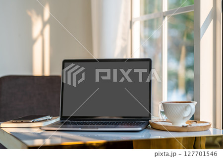 Mockup of laptop computer with empty screen with coffee cup and smartphone on table beside the window of the coffee shop background,Black gray screen 127701546