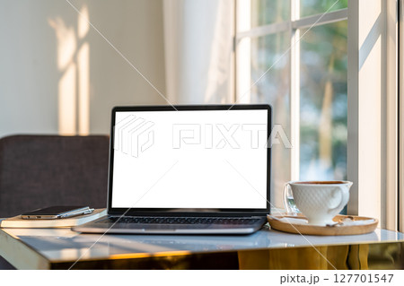 Mockup of laptop computer with empty screen with coffee cup and smartphone on table beside the window of the coffee shop background,White screen 127701547
