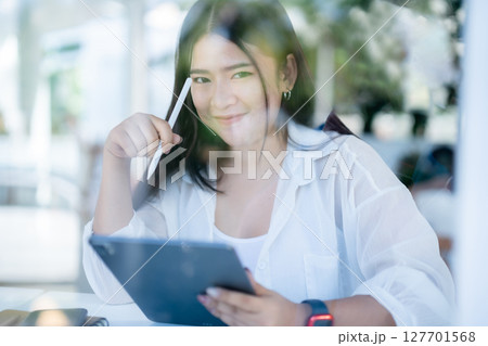 asian freelance people business female wearing smartwatch talking making using casual working with tablet for browsing internet, chatting and blogging and smartphone,notebook in coffee shop. 127701568